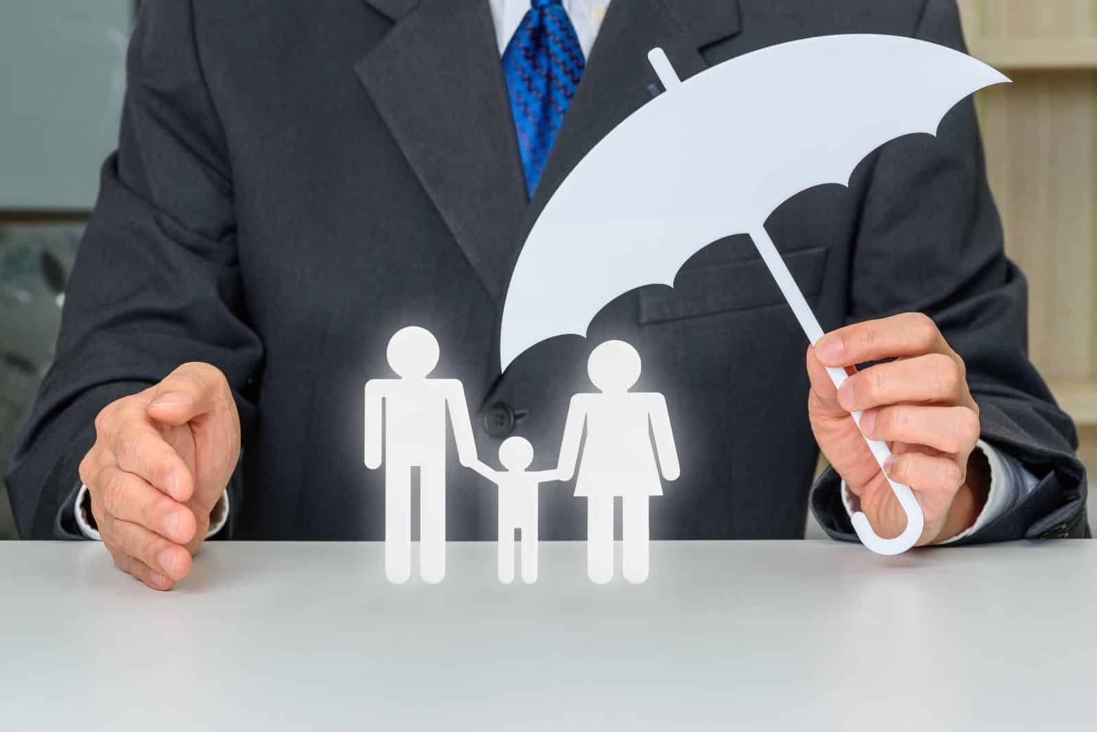 Final expense insurance agent protecting paper family under paper umbrella